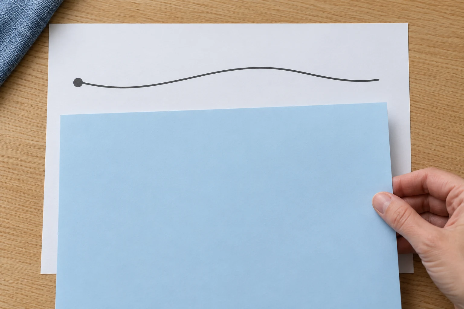 Keep the selected route and starting cue visible An adult hand holds a pale blue cover over the lower part of a white sheet, leaving a broad curved route and starting dot visible above it.